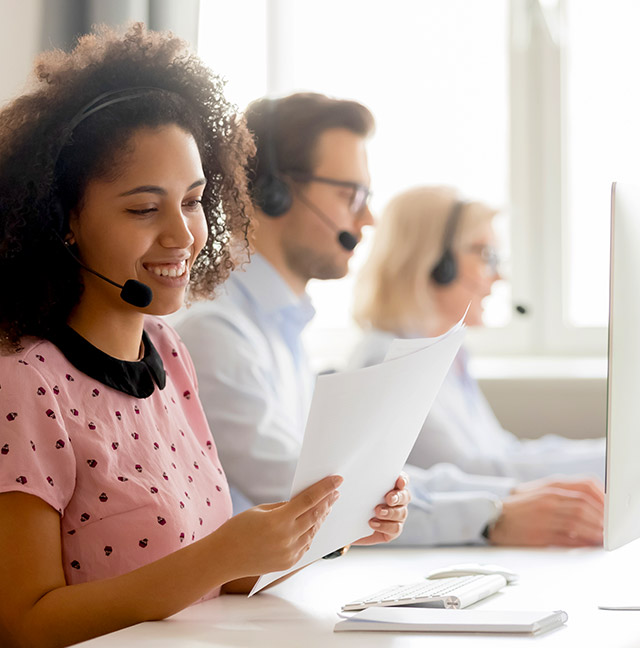 Woman using headset to talk with customer while on desktop computer